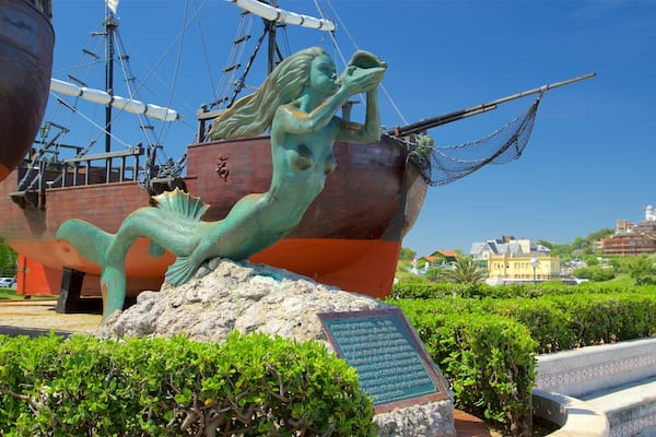 Eine bronzene Statue einer Meerjungfrau, im Hintergrund ein Schiff.