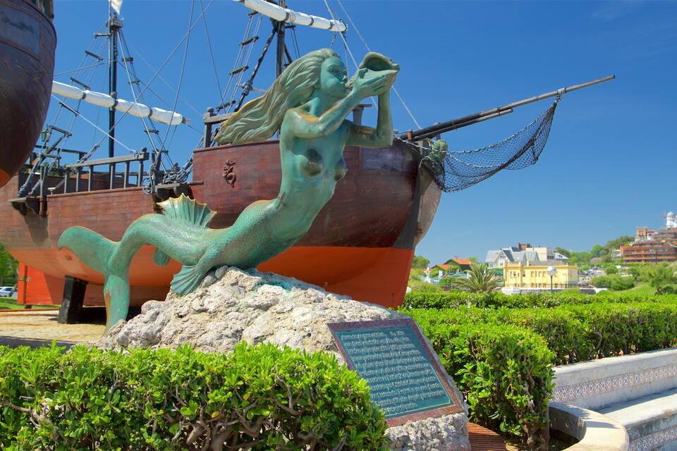A bronze statue of a mermaid with a ship in the background.
