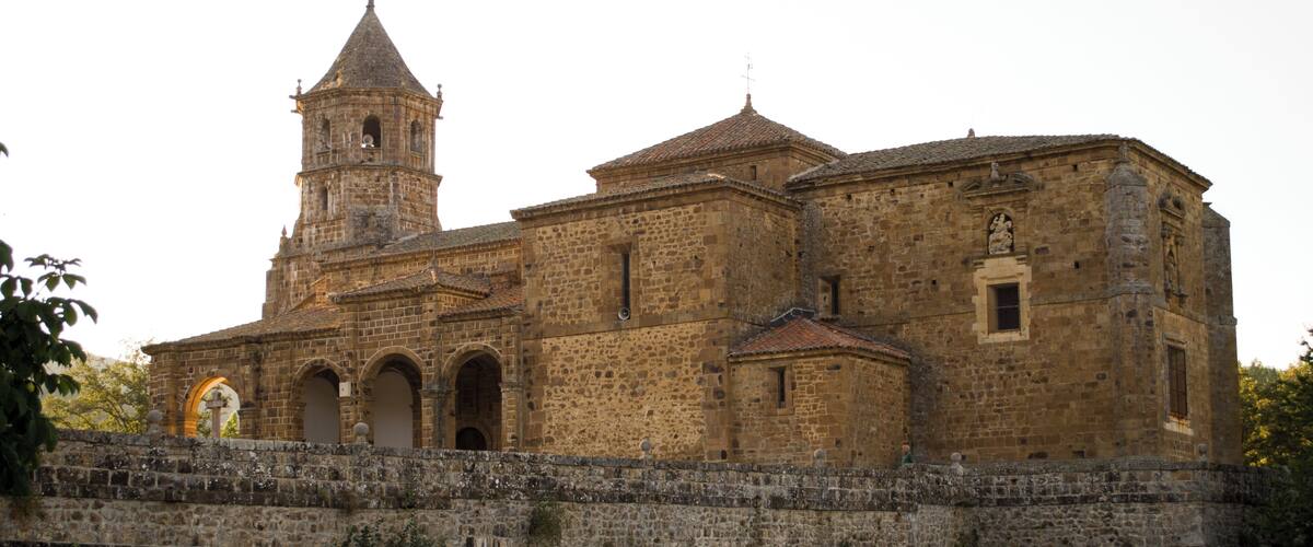 A historic stone church with a bell tower and a fortified wall.