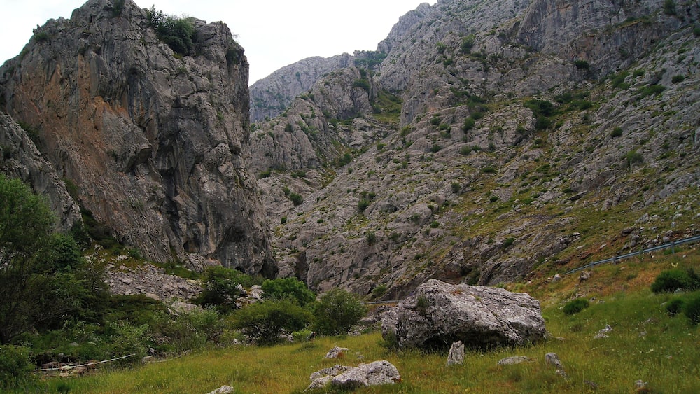 A rugged mountainous landscape with rocky cliffs and sparse vegetation.