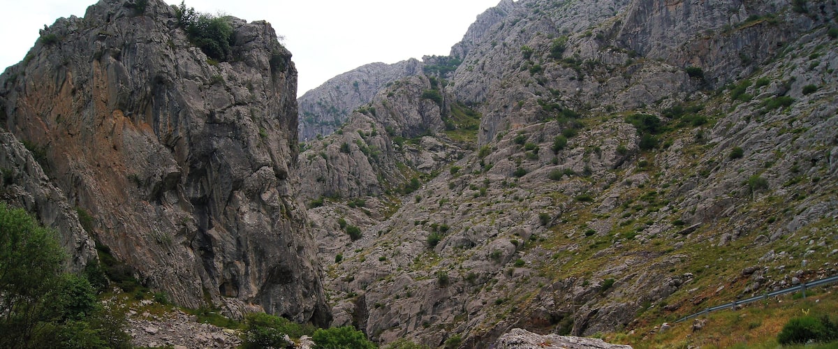 A rugged mountainous landscape with rocky cliffs and sparse vegetation.