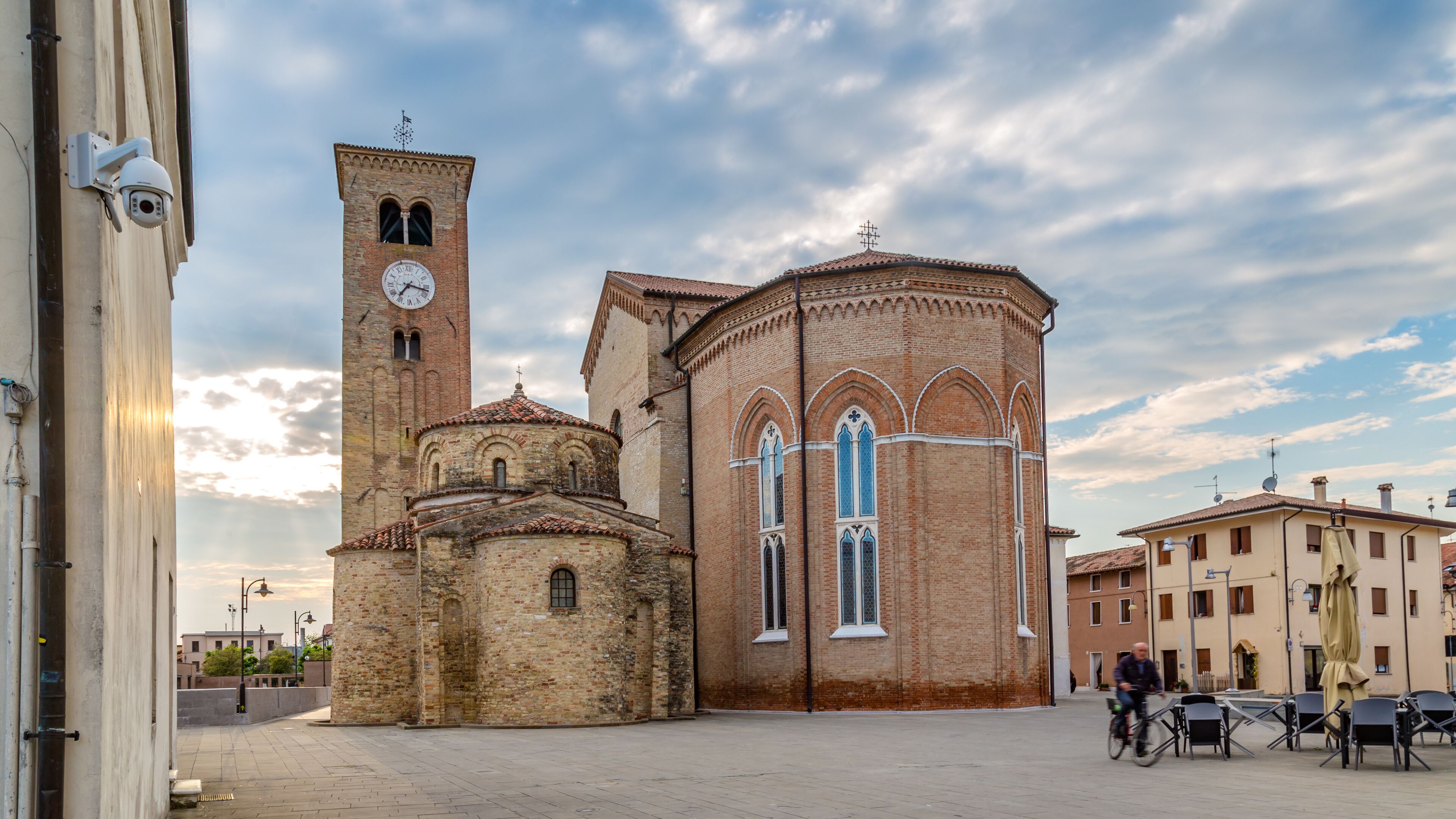 A historic church with a bell tower and a dome, surrounded by a paved square and buildings.