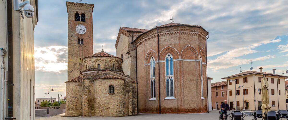 A historic church with a bell tower and a dome, surrounded by a paved square and buildings.