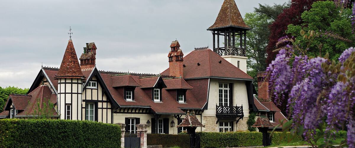 A traditional Tudor-style house with multiple chimneys and a bell tower.
