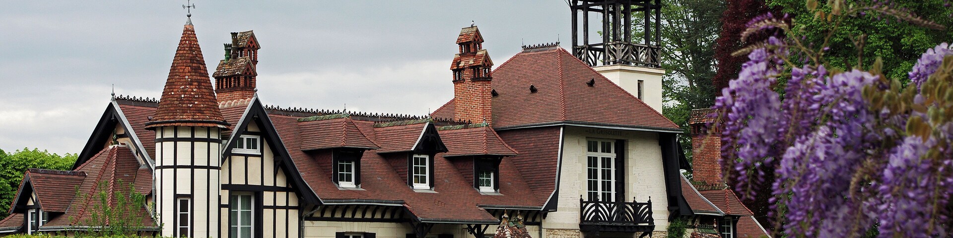 A traditional Tudor-style house with multiple chimneys and a bell tower.