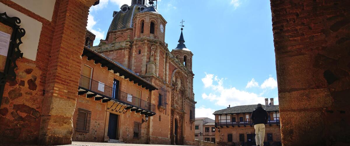 A cobblestone street leading to a historic church with a bell tower and a clock.