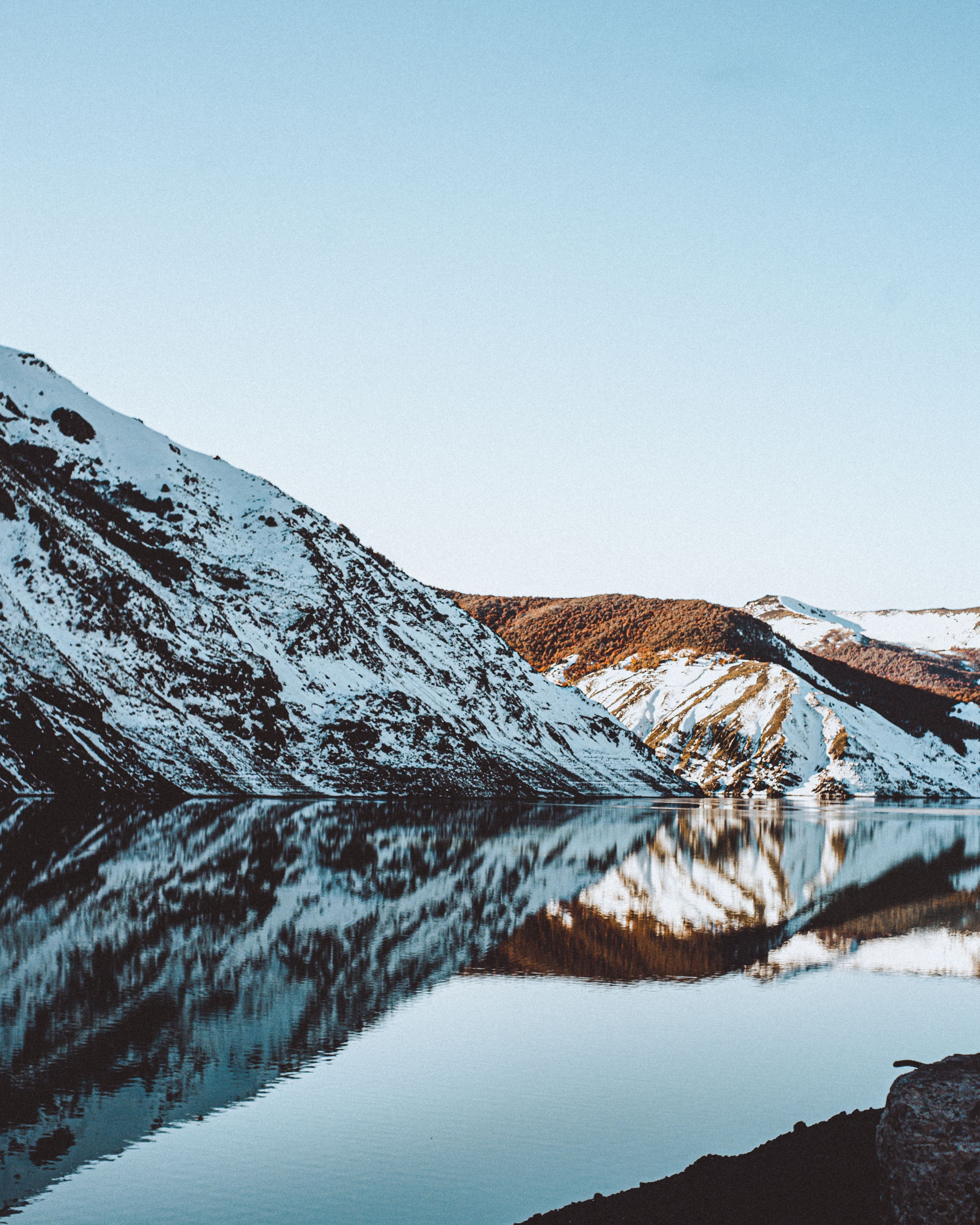 A snow-covered mountain range reflecting in a calm lake.