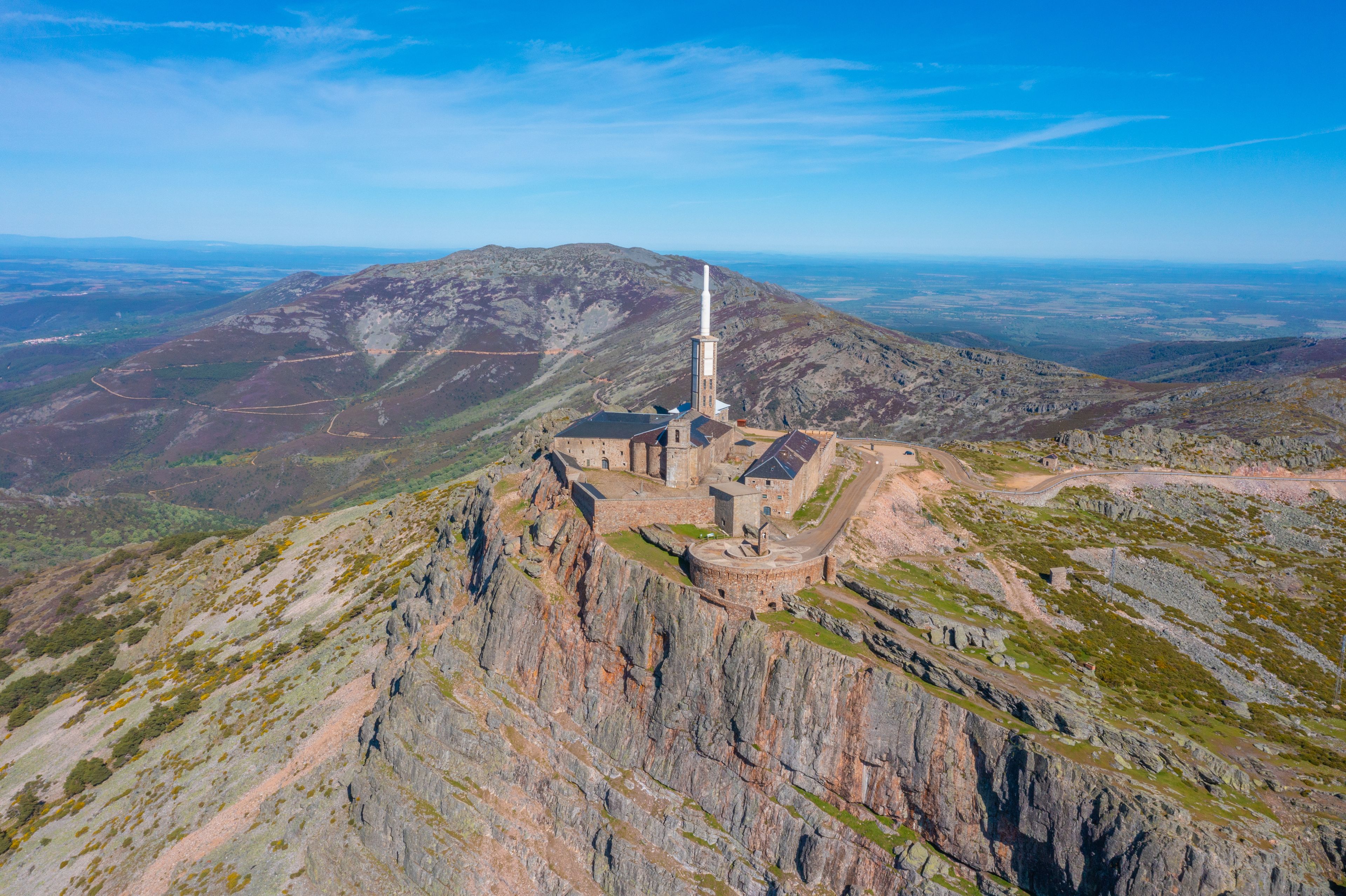 A historic stone building with a tall chimney on a mountain peak.