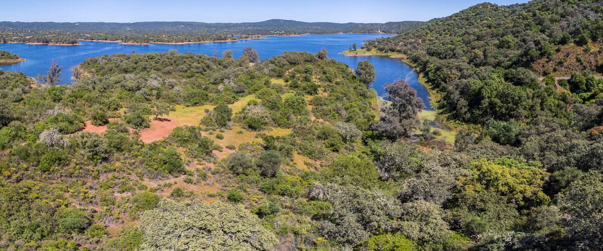 A large lake surrounded by dense forest and hills.