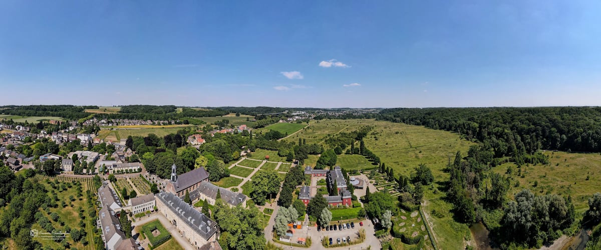 An aerial view of a historic estate with expansive gardens, a large manor house, and surrounding fields.