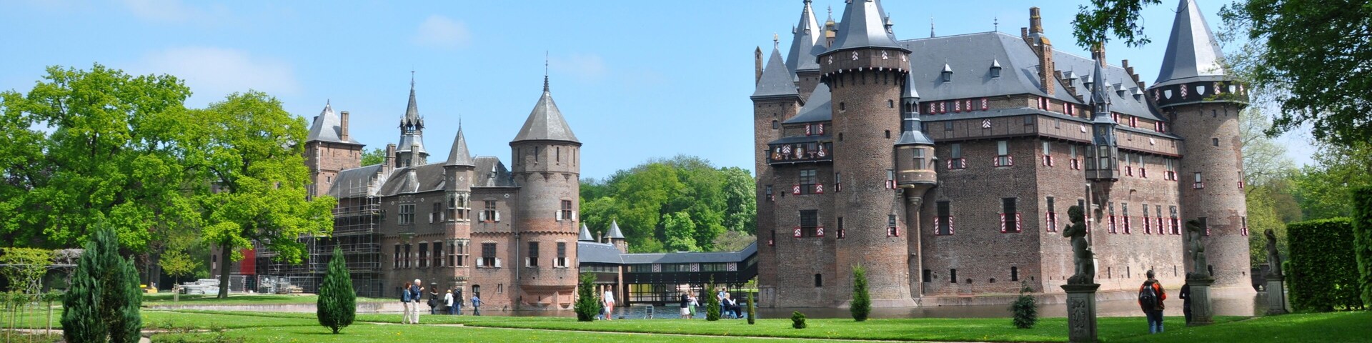 Un gran castillo histórico con múltiples torres y un jardín bien cuidado.