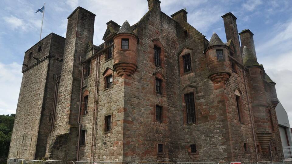 A large stone castle with multiple towers and a flag on top.