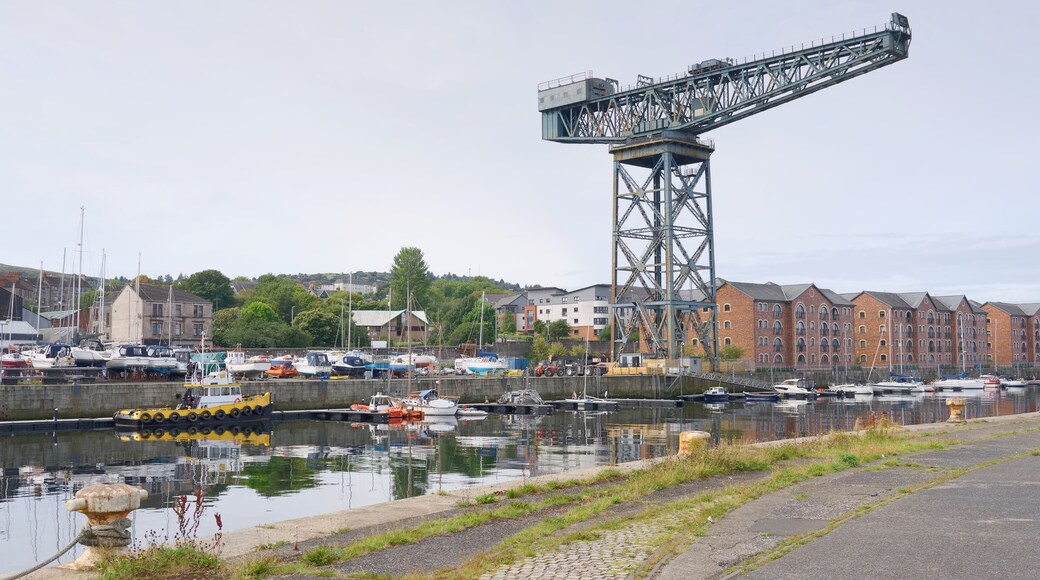 A harbor with boats, a large crane, and buildings in the background.