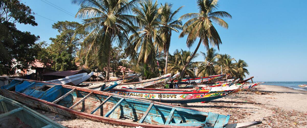 A beach with several colorful boats and palm trees.