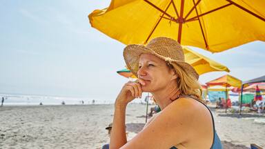 Female tourist sitting under beach umbrella, Camana, Arequipa, Peru