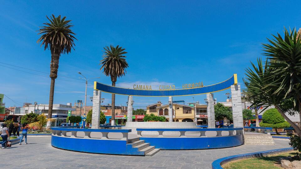 A circular plaza with a blue and white structure, palm trees, and a clear blue sky.
