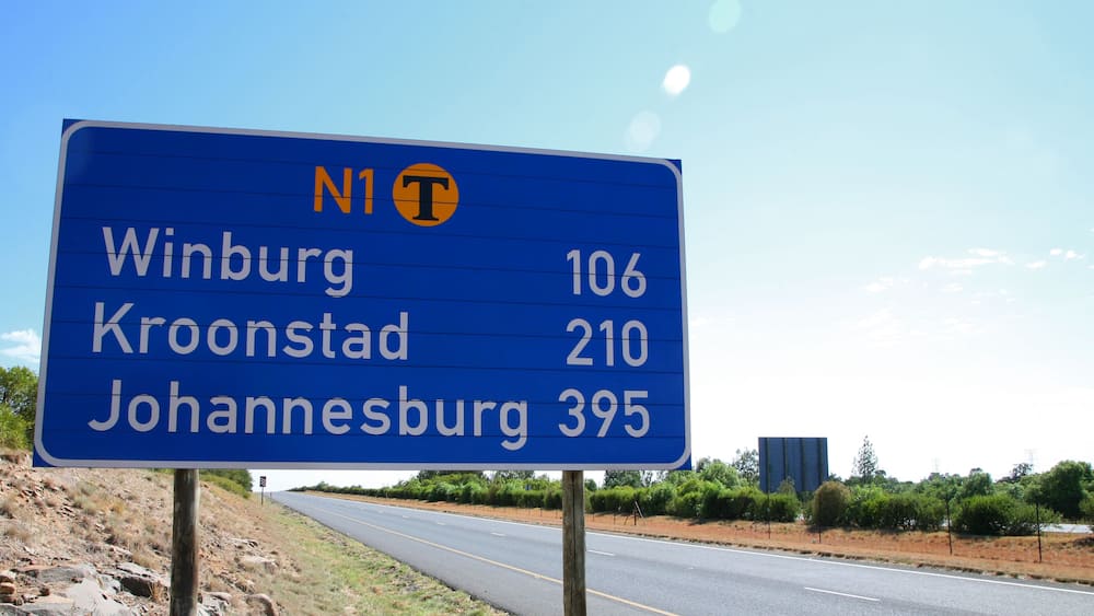 A highway sign with destinations and distances: Winburg 106, Kroonstad 210, Johannesburg 395.