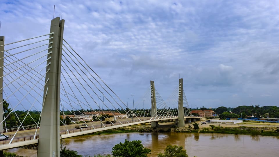 A cable-stayed bridge over a river with a cloudy sky.