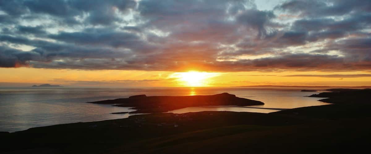 A sunset over a coastal landscape with cliffs and a body of water.
