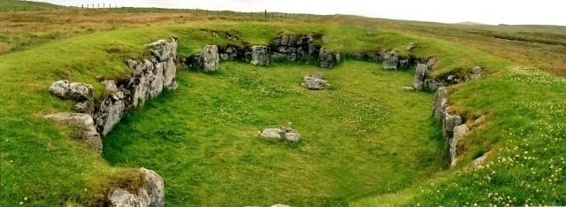 A stone circle surrounded by grassy fields.