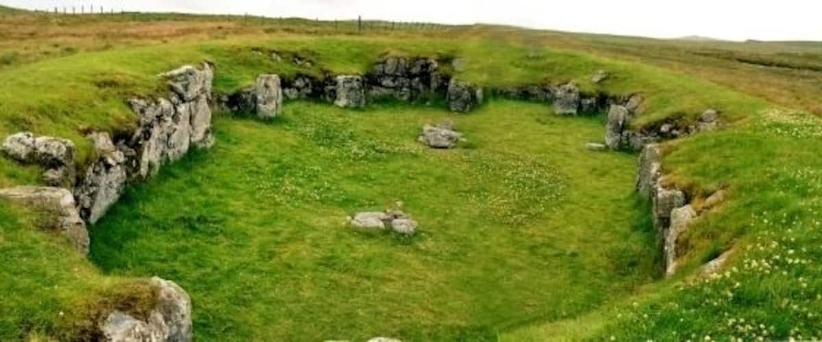A stone circle surrounded by grassy fields.