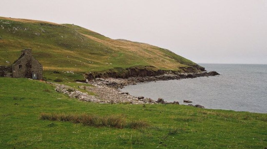 Beach of East Lunna Voe The photo is taken south of Lunna Kirk. The building appears to be deserted - perhaps an old farm? Erosion of the hillside behind the beach is evident from the exposed face with minor slips.