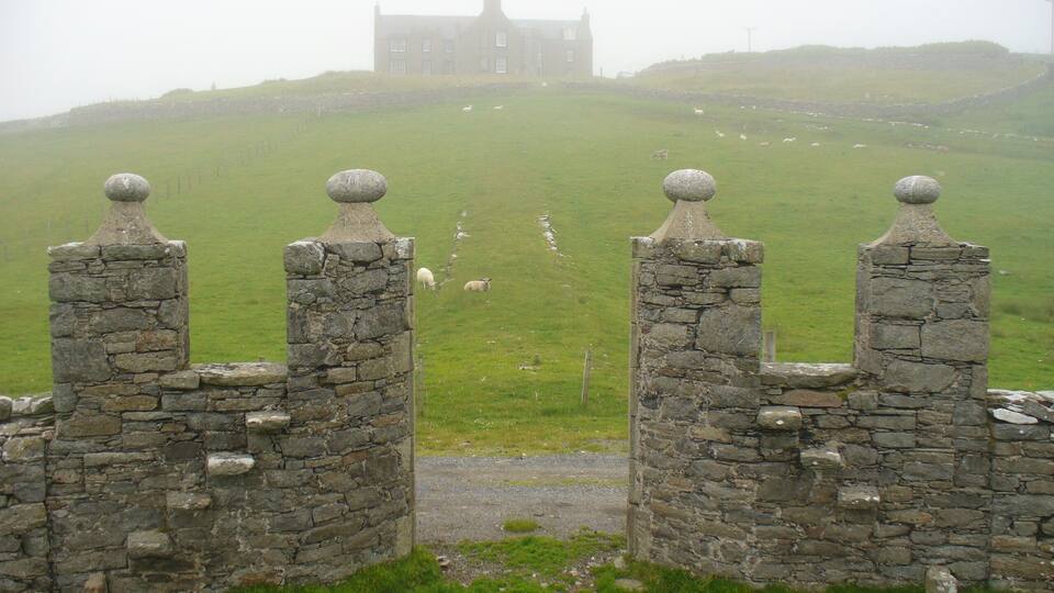 A stone gate with a view of a castle on a hill.