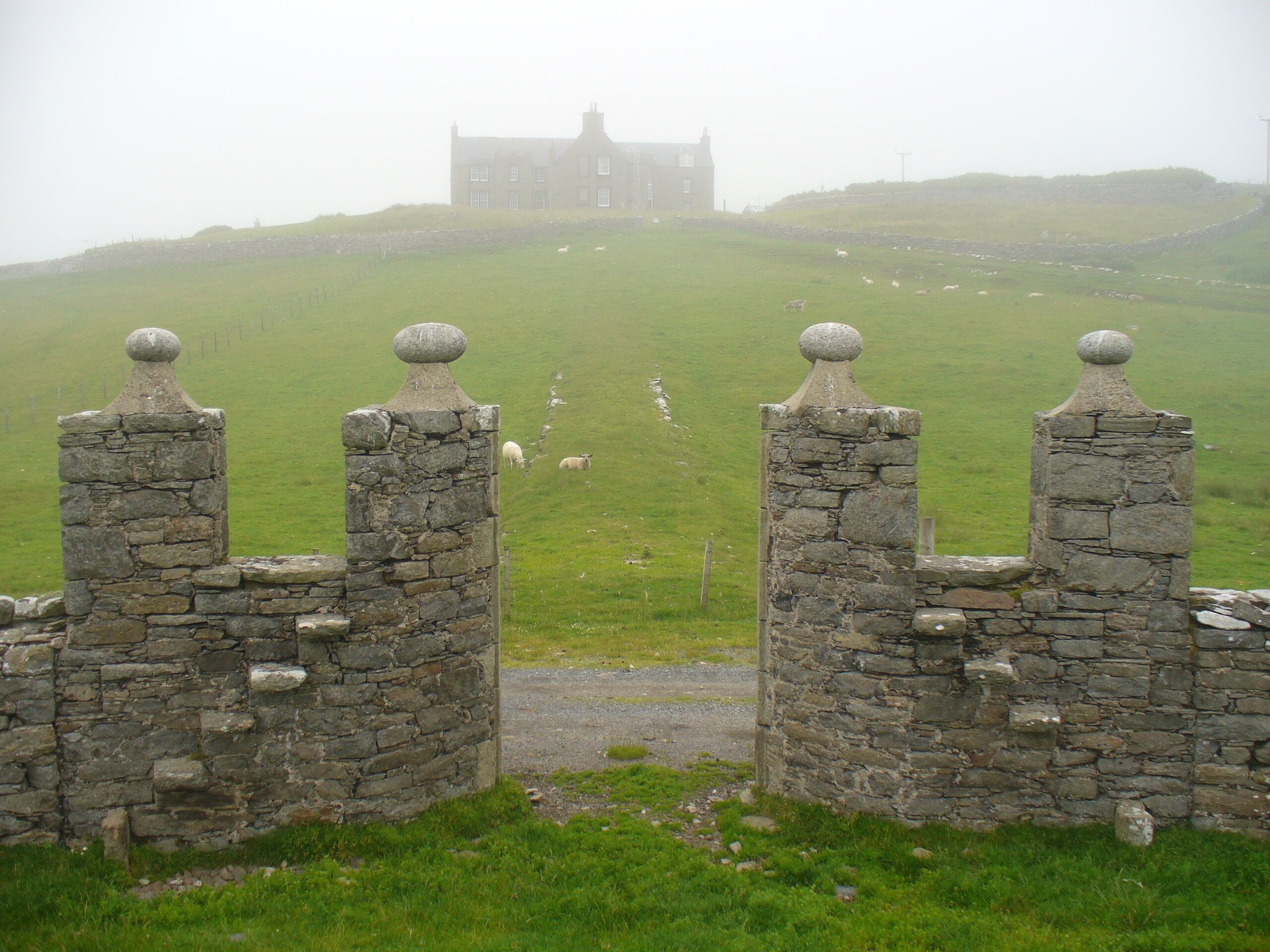 A stone gate with a view of a castle on a hill.