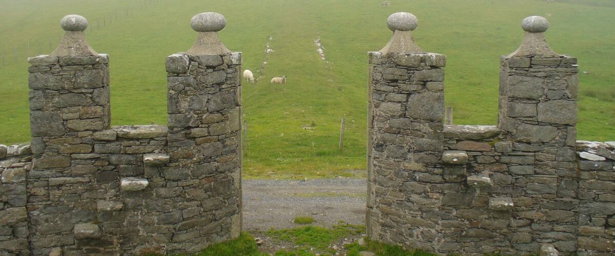 A stone gate with a view of a castle on a hill.