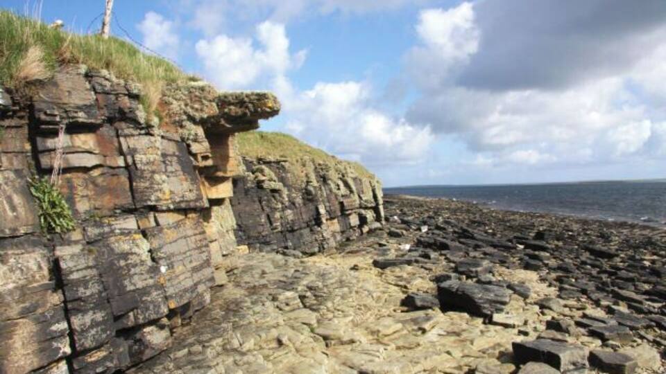 A rocky coastline with layered cliffs and a beach.