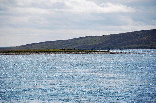 A calm body of water with a distant shoreline and hills.