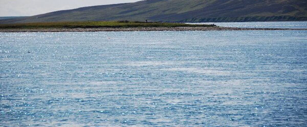 A calm body of water with a distant shoreline and hills.