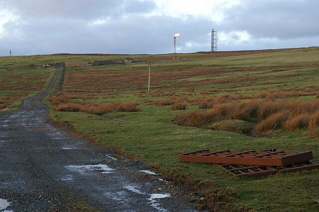 Slopes of the Hill of Garth Looking up the track towards a sheep pund, with the flare stack on the top of the Hill of Garth in the distance.