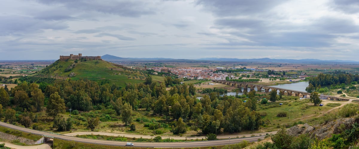 A castle on a hill, a bridge over a river, and a town in the valley.