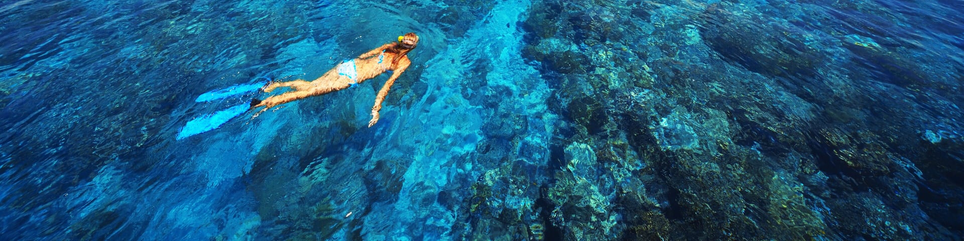 Young woman snorkeling in transparent shallow sea near boat