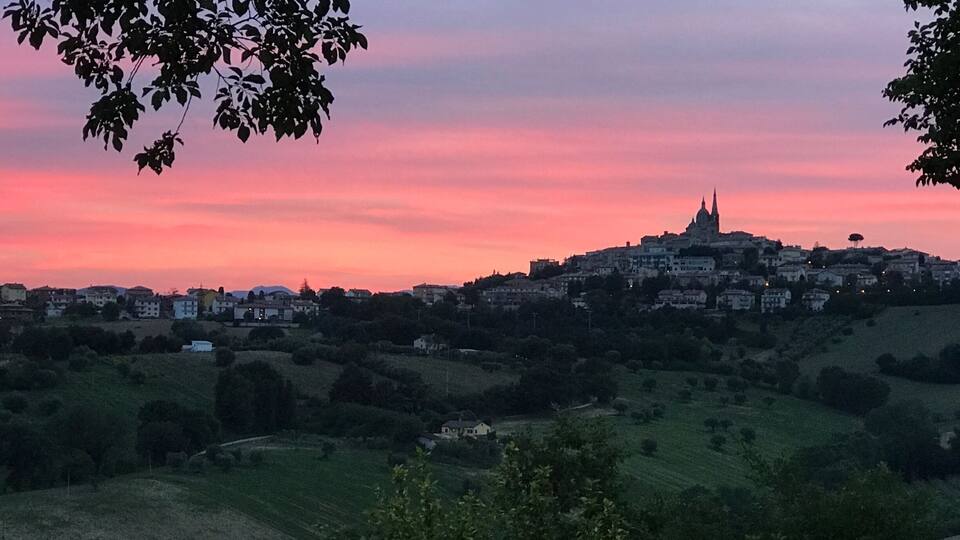 A sunset over a town with a prominent church on a hill.