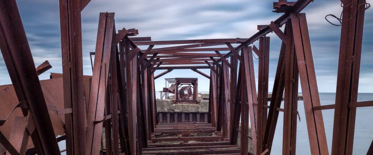A rusted metal bridge structure extending over water.