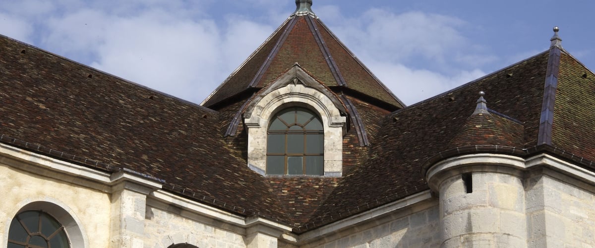 A historic building with a steeply pitched roof, arched windows, and a prominent central tower.