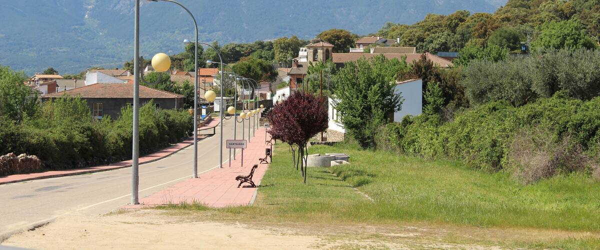Eine Straße mit einer Bank, Straßenlaternen und einem Berg im Hintergrund.