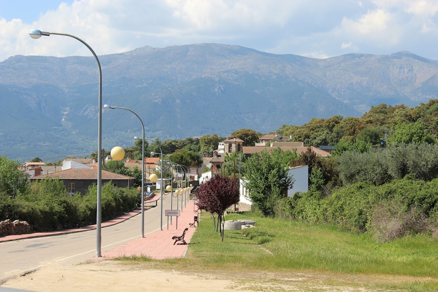 Un carrer amb una banca, fanals i una muntanya al fons.