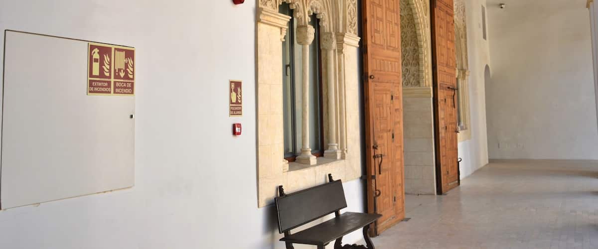 An ornate hallway with intricate architectural details, a wooden door, and a bench.