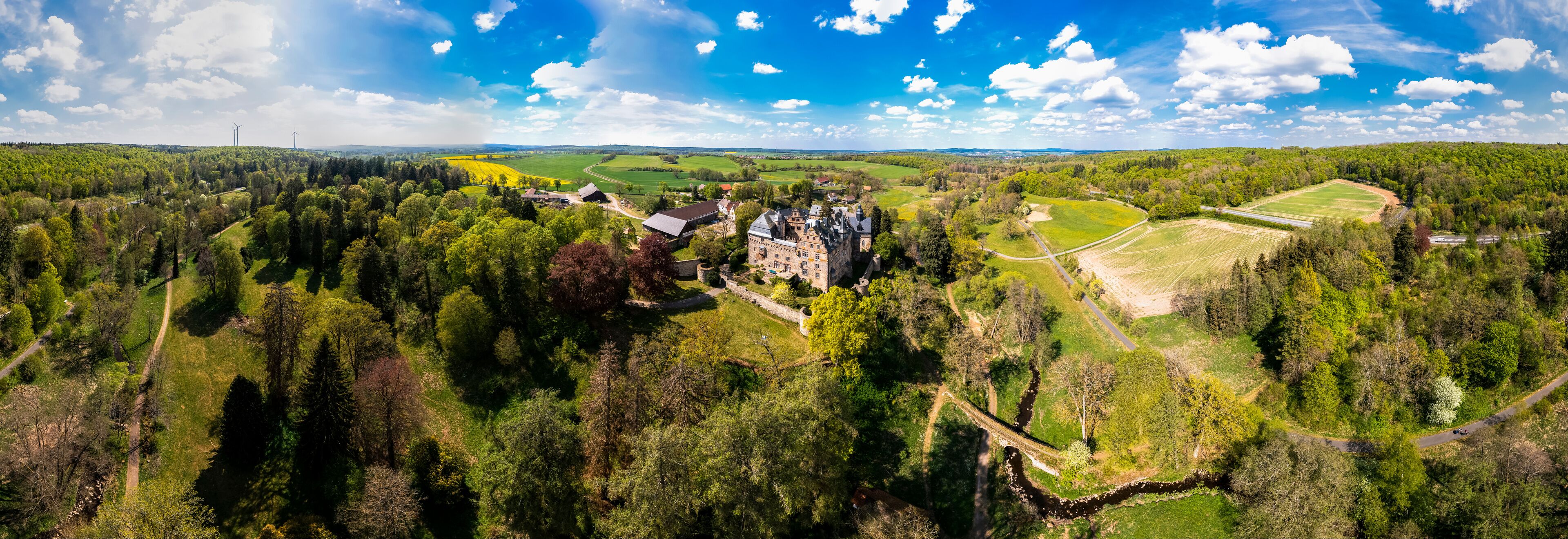 A castle surrounded by dense forests and fields.