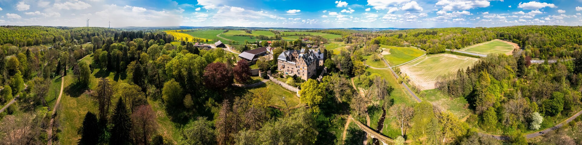 A castle surrounded by dense forests and fields.