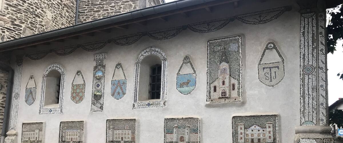 A building with mosaic windows and a patterned stone base.