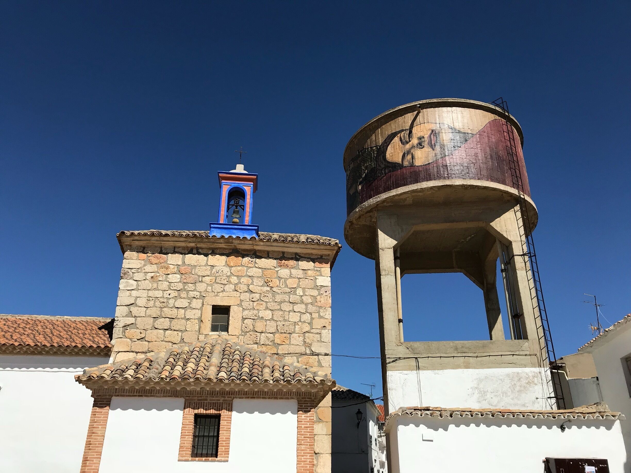A stone tower with a bell and a water tower.