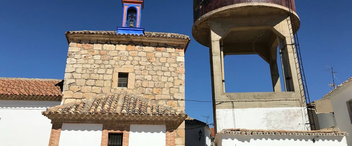 A stone tower with a bell and a water tower.