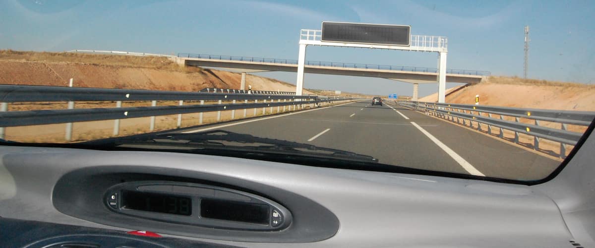 A highway with a bridge overhead and a clear blue sky.