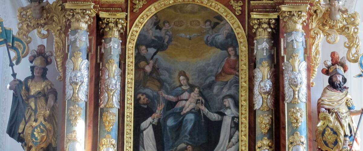 A richly decorated altar with a central painting, ornate columns, and statues.