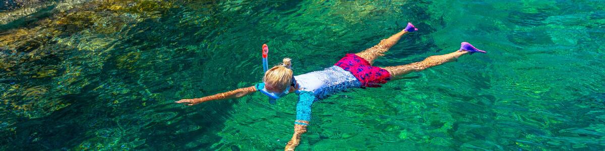Top view of snorkeler in Sant 'Andrea beach Cote Piane side with rocks and coves, Elba island. Woman in clear waters of Tyrrhenian sea on holiday travel, Italy. Saint Andrew is popular seaside resort.