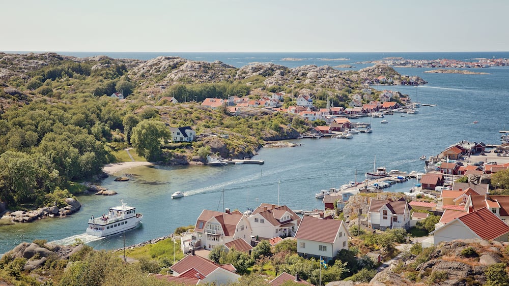 A coastal village with houses, a boat, and rocky terrain.
